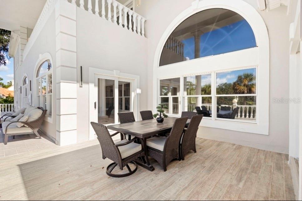 A covered outdoor patio features a dining set, tile flooring, and large arched windows — 1126 BROWNSHIRE COURT, LONGWOOD, FL