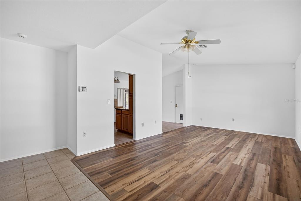 A living room with wood-look flooring, white walls, a ceiling fan, and a tiled entryway — 141 AVENS STREET, PORT CHARLOTTE, FL