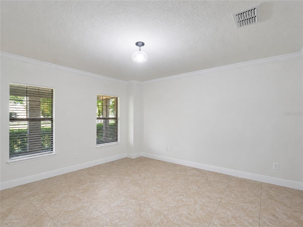 An empty room with white walls, tile flooring, two windows, and a ceiling light fixture — 10862 SUNSET RIDGE LANE, ORLANDO, FL