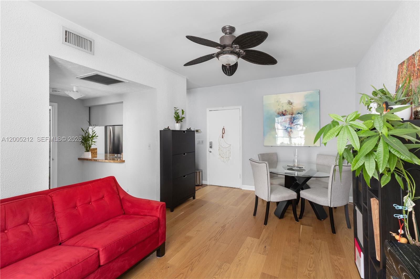 A living and dining area features a red sofa, glass-topped table, and light wood flooring — 1200 Euclid Ave # 102, Miami Beach FL 33139, MIAMI BEACH, FL