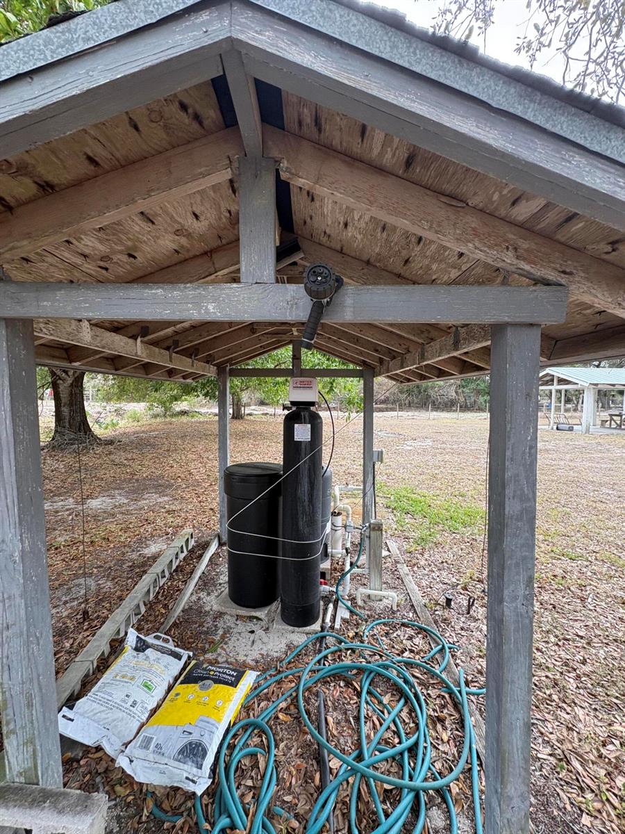 A water softener system sits under a wooden shelter in a grassy outdoor area — 230 N Brida Street, Clewiston FL 33440, CLEWISTON, FL