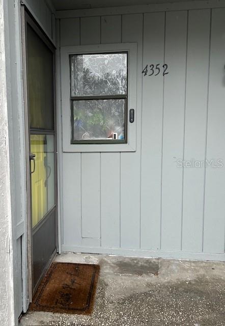 A gray exterior wall features a window, a door with a screen, and a doormat — 4352 AQUA VISTA DRIVE UNIT 9D, ORLANDO, FL