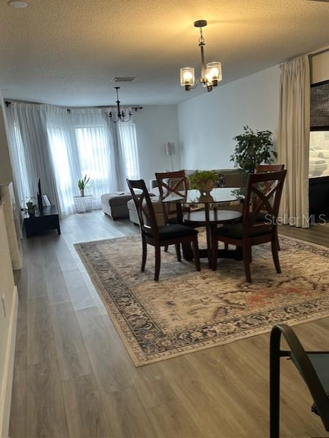 A dining area with a glass table and chairs sits on a rug near windows — 4352 AQUA VISTA DRIVE UNIT 9D, ORLANDO, FL