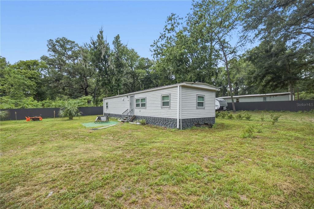 A single-story manufactured home with light siding sits on a large, grassy lot — 5620 SE 29TH COURT, OCALA, FL