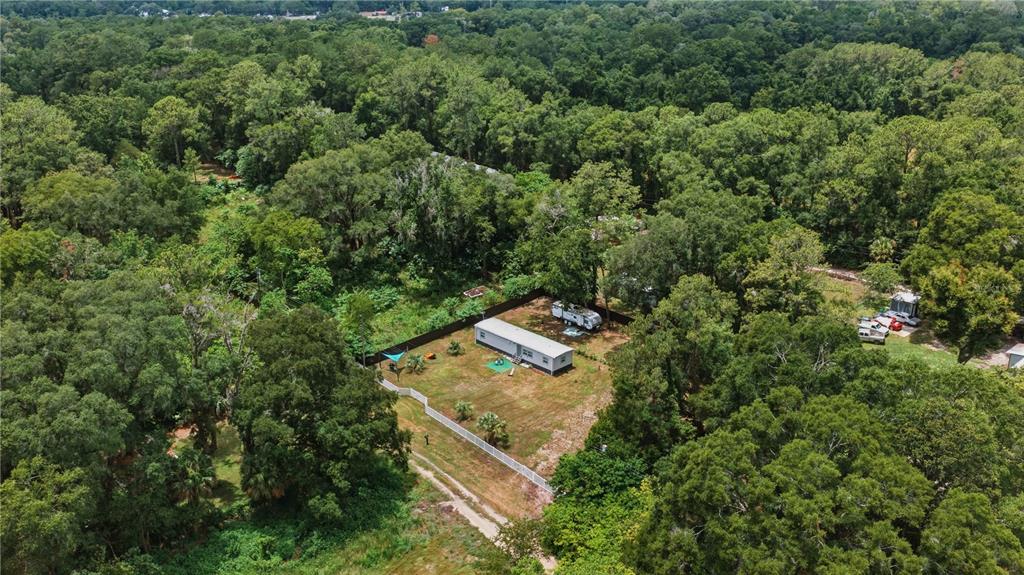 An aerial view shows a single-story manufactured home situated on a large, tree-lined grassy lot — 5620 SE 29TH COURT, OCALA, FL