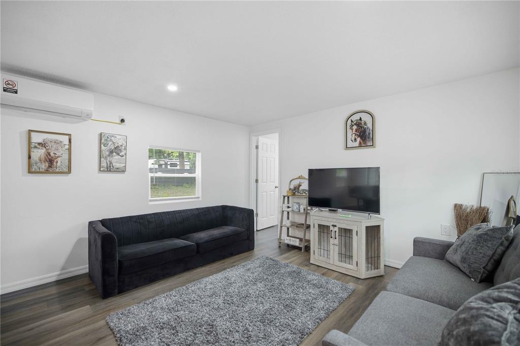 A living room features two sofas, a television on a media console, and wood-look flooring — 5620 SE 29TH COURT, OCALA, FL