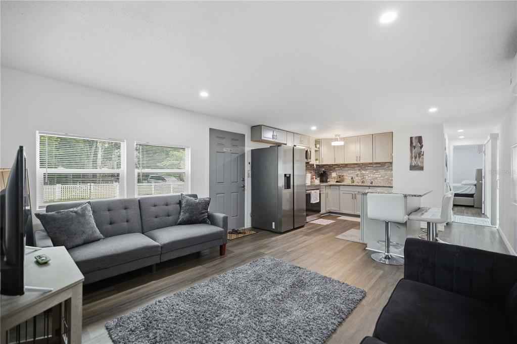 A living room with a grey sofa and kitchen area featuring stainless steel appliances — 5620 SE 29TH COURT, OCALA, FL