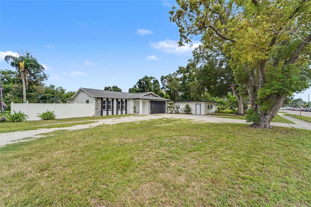 A single-story house with a white fence, a gravel driveway, and a large tree — 11635 131ST STREET, LARGO, FL