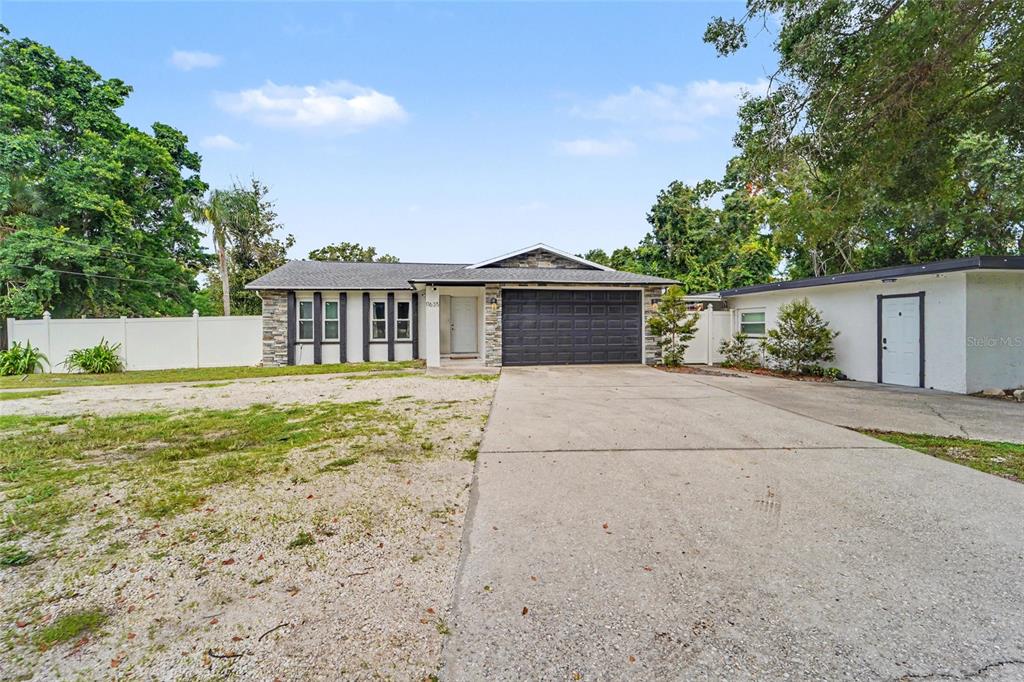 A single-story house features a stone facade, a dark garage door, and a concrete driveway — 11635 131ST STREET, LARGO, FL
