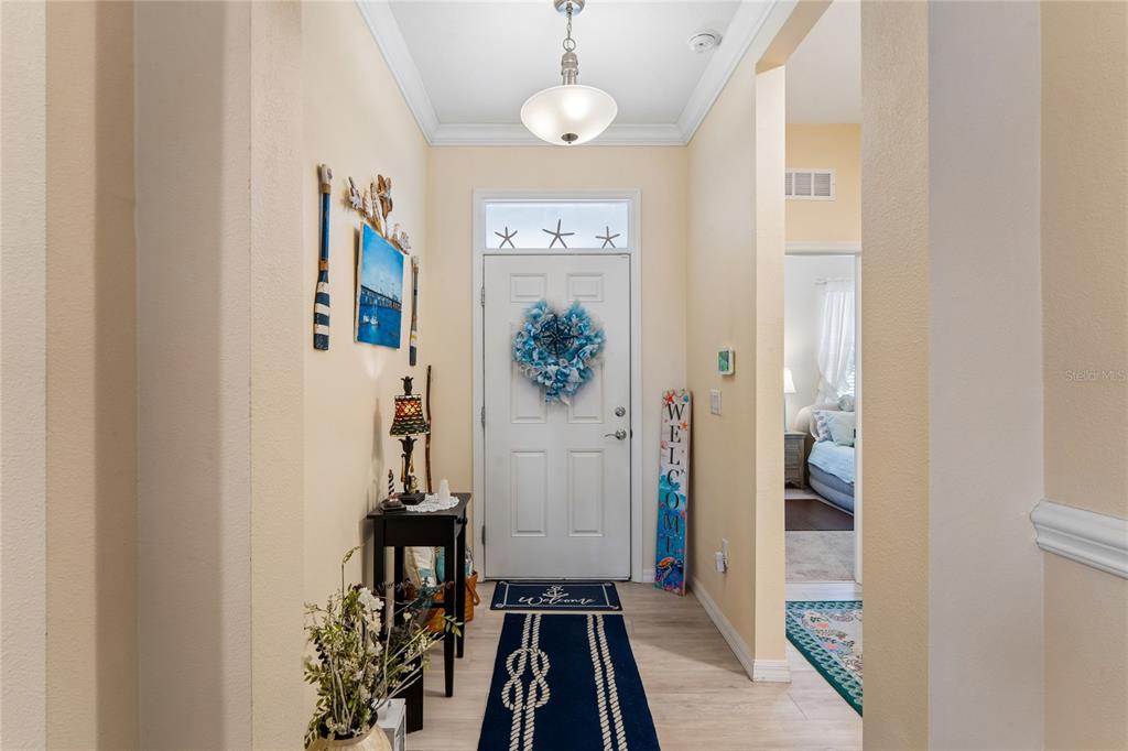 A bright entryway features a white front door, coastal decor, and a blue runner rug — 13605 PADDINGTON WAY, SPRING HILL, FL