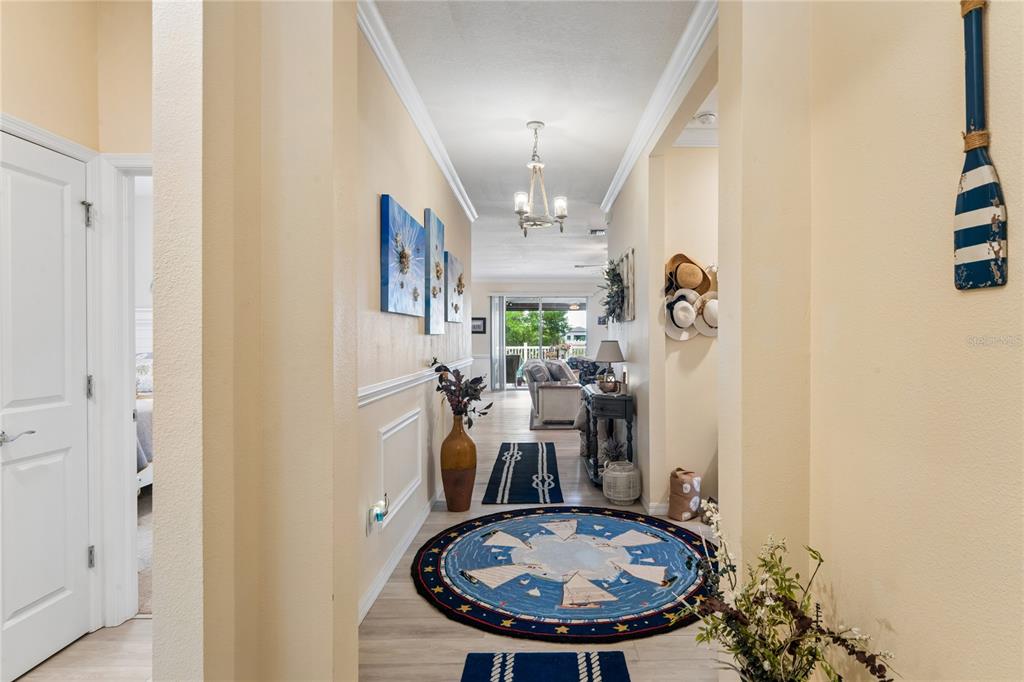 A hallway with light walls, a round nautical rug, and a view into the living area — 13605 PADDINGTON WAY, SPRING HILL, FL