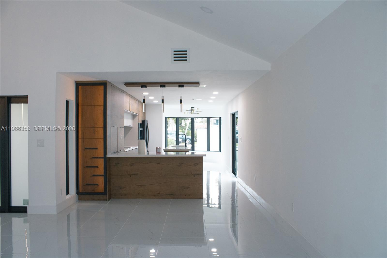 A modern kitchen features wood-toned cabinetry, a central island, and white tile flooring — 10433 SW 118th Ct, Miami FL 33186, MIAMI, FL