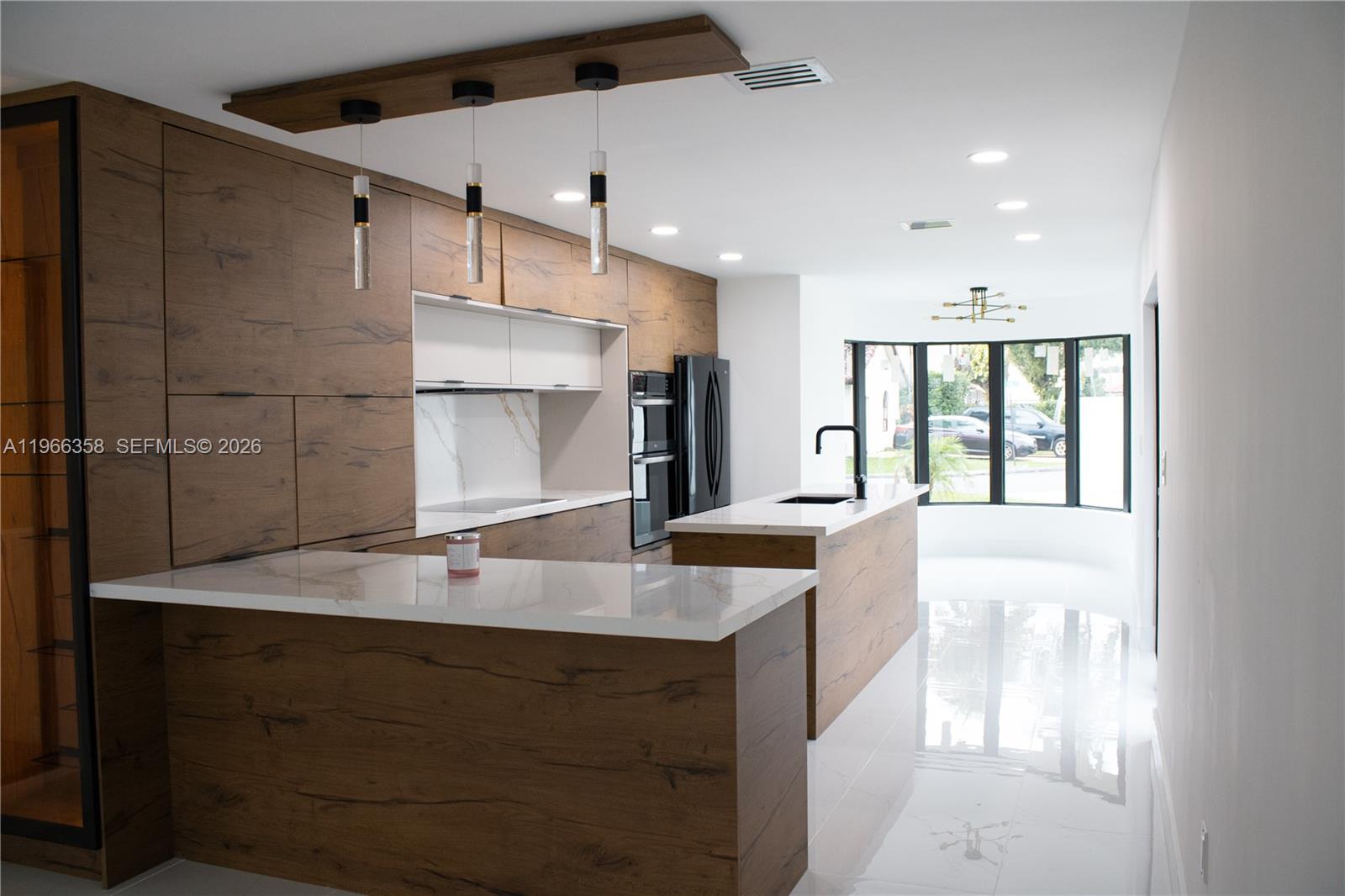 A modern kitchen features wood-grain cabinetry, white marble countertops, and a central island — 10433 SW 118th Ct, Miami FL 33186, MIAMI, FL