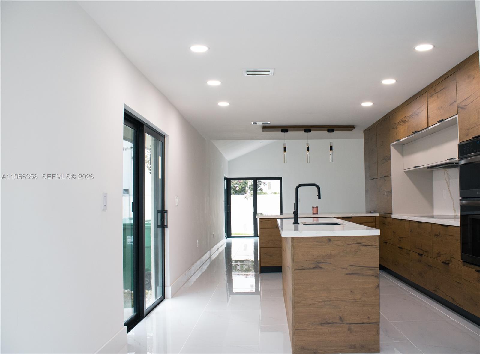 A modern kitchen features wood-grain cabinetry, a central island, and white tile flooring — 10433 SW 118th Ct, Miami FL 33186, MIAMI, FL