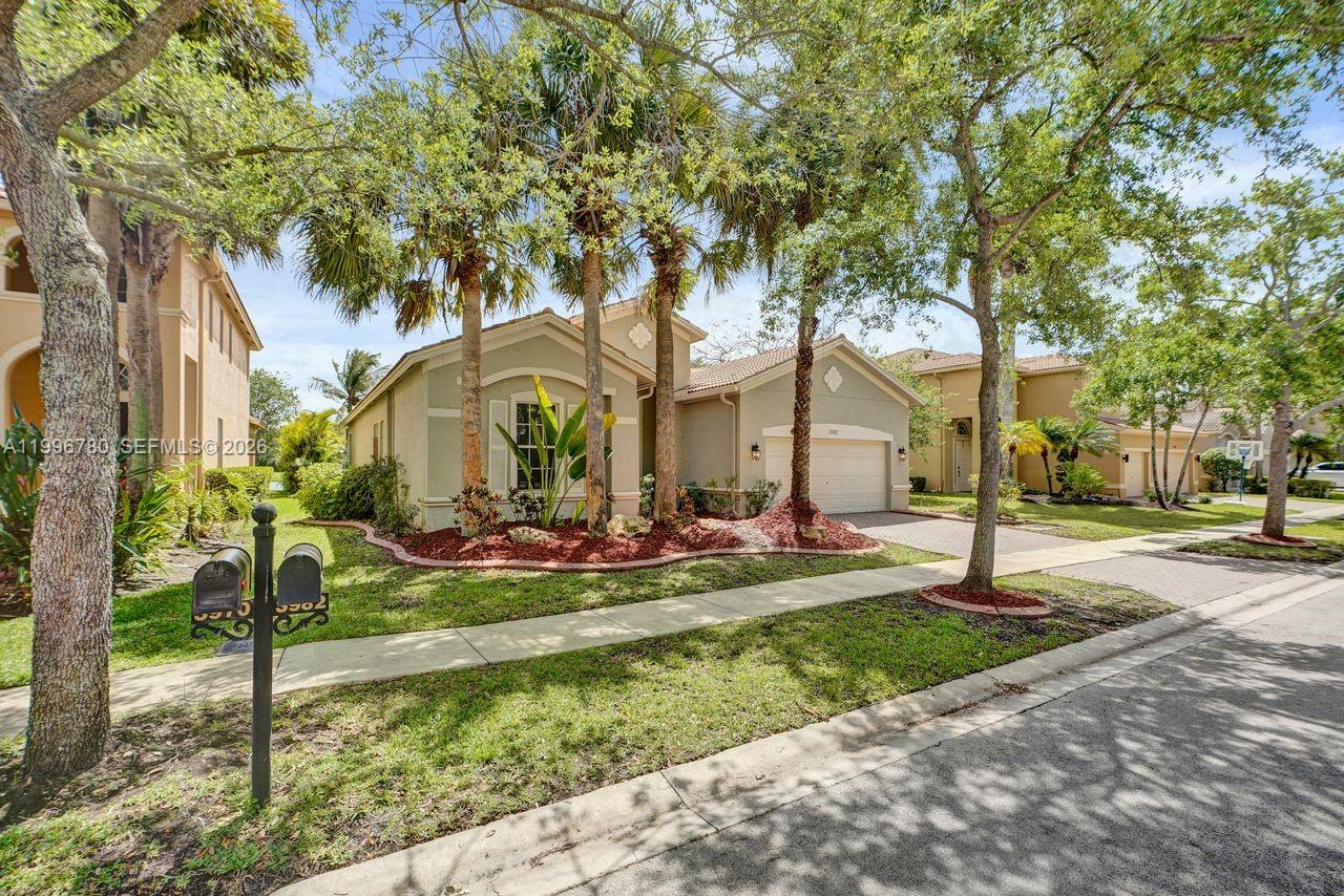 A single-story suburban house with a tan stucco exterior, a garage, and palm trees — 3982 W Whitewater Ave, Weston FL 33332, WESTON, FL