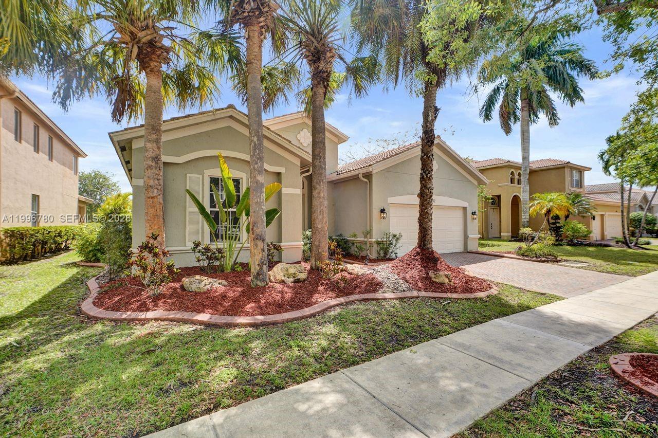 A single-story house with a beige stucco exterior, a two-car garage, and palm trees — 3982 W Whitewater Ave, Weston FL 33332, WESTON, FL