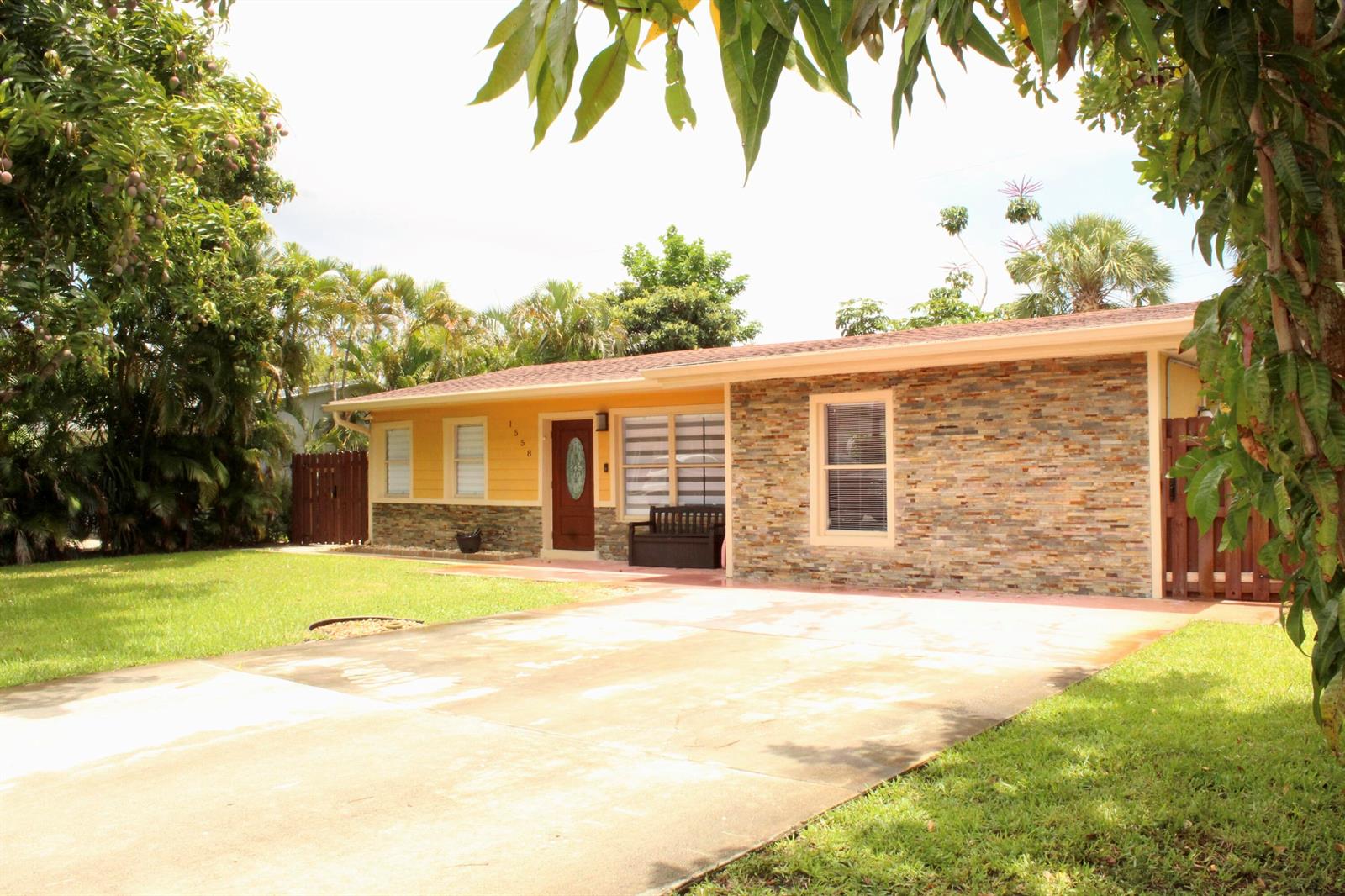 A single-story house with yellow siding, stone veneer, and a concrete driveway — 1558 NE 30th Street, Pompano Beach FL 33064, POMPANO BEACH, FL