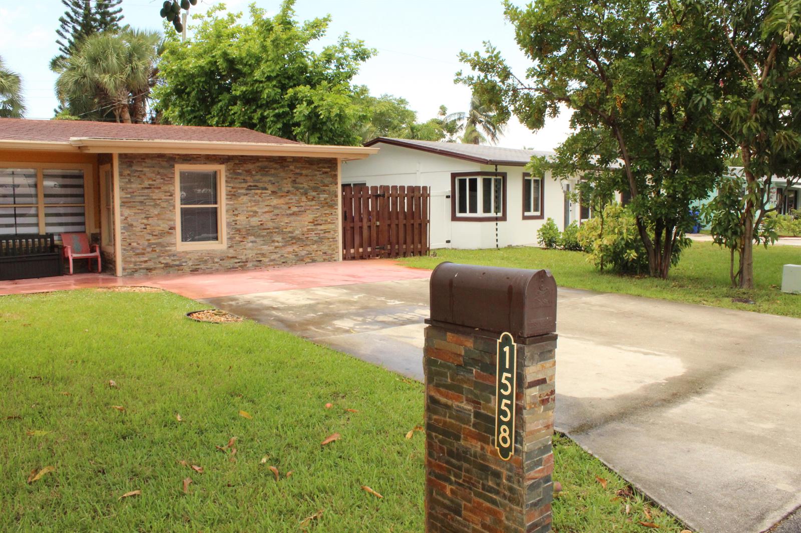 A stone-faced mailbox stands in front of a house with a stone-veneer exterior — 1558 NE 30th Street, Pompano Beach FL 33064, POMPANO BEACH, FL