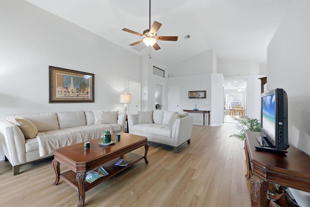 A living room features light-colored sofas, a wooden coffee table, and a vaulted ceiling — 1468 TURNBERRY DRIVE, VENICE, FL