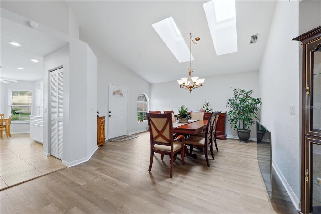 A dining room with wood-look flooring, a vaulted ceiling with skylights, and a chandelier — 1468 TURNBERRY DRIVE, VENICE, FL