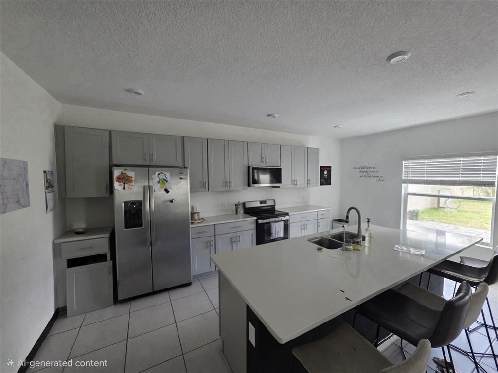 A kitchen features gray cabinets, stainless steel appliances, a large island, and tile flooring — 5721 SAGUNTO DRIVE, DAVENPORT, FL
