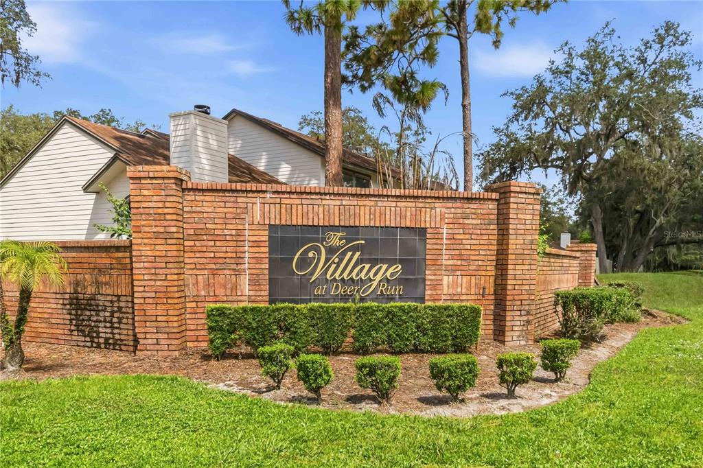 A brick wall with a sign reading The Village at Deer Run stands outdoors — 4008 W MARYLAND PLACE, CASSELBERRY, FL