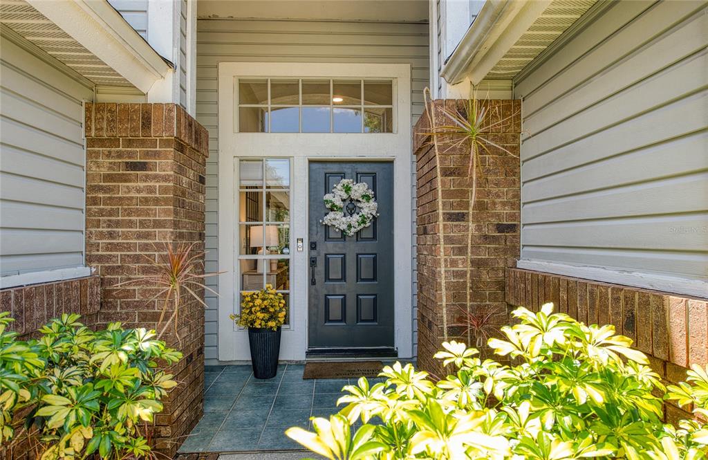 A front entryway features a dark gray door with a wreath, sidelight, and brick columns — 2182 TREVOR ROAD, PALM HARBOR, FL