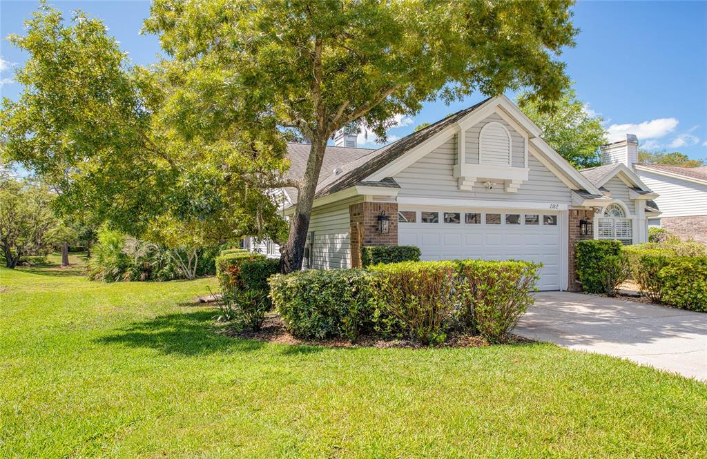 A single-story house with light gray siding, a two-car garage, and a large front tree — 2182 TREVOR ROAD, PALM HARBOR, FL