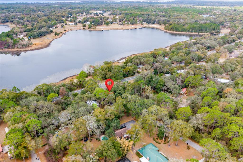 An aerial view shows a house nestled among trees near a large lake — 1353 CHATAUQUA WAY, KEYSTONE HEIGHTS, FL