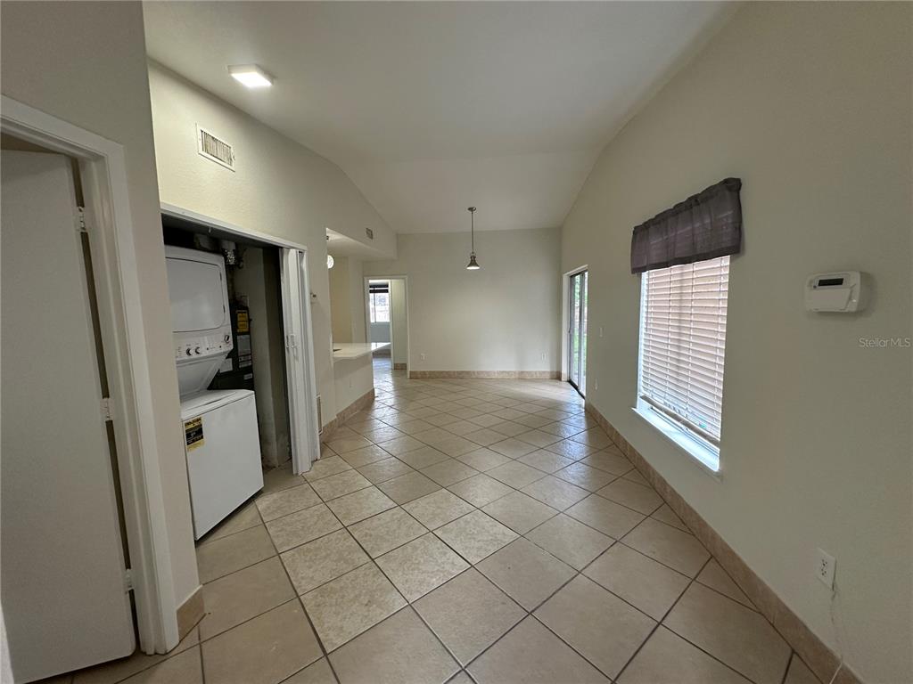 A room with tiled floors, a stacked washer and dryer, and a window with blinds — 1000 DOLPHIN DRIVE, WINTER GARDEN, FL