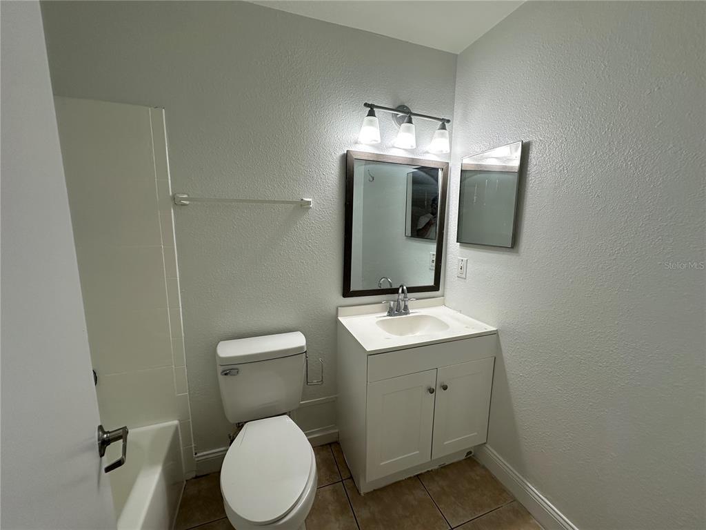 A bathroom features a white vanity, a toilet, a bathtub, and a framed mirror — 1000 DOLPHIN DRIVE, WINTER GARDEN, FL
