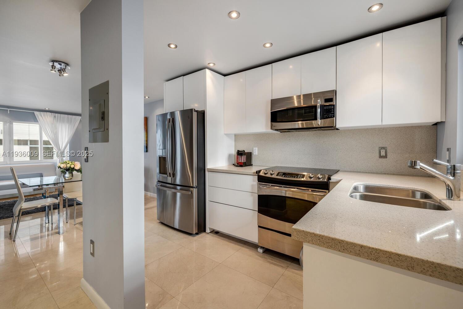 A modern kitchen features white flat-panel cabinets, stainless steel appliances, and light-colored stone countertops — 325 Ocean Dr # 409, Miami Beach FL 33139, MIAMI BEACH, FL