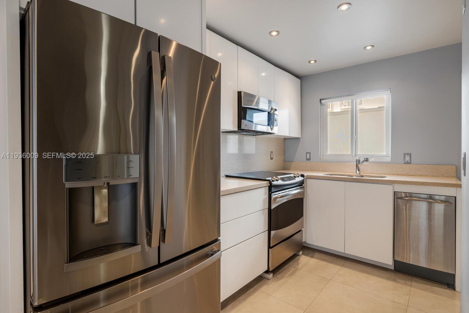 A kitchen features stainless steel appliances, white cabinetry, and light-colored countertops — 325 Ocean Dr # 409, Miami Beach FL 33139, MIAMI BEACH, FL