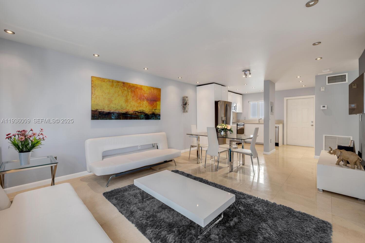 A modern living and dining area features white furniture, a grey rug, and tile flooring — 325 Ocean Dr # 409, Miami Beach FL 33139, MIAMI BEACH, FL