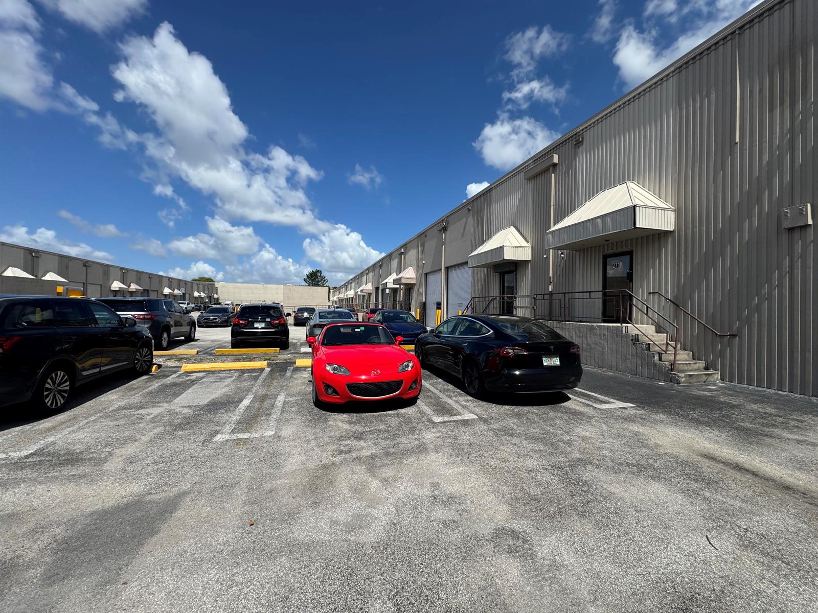 A red convertible and a black sedan are parked in front of a commercial building — 2710 NW 72nd Avenue, Miami FL 33122, MIAMI, FL
