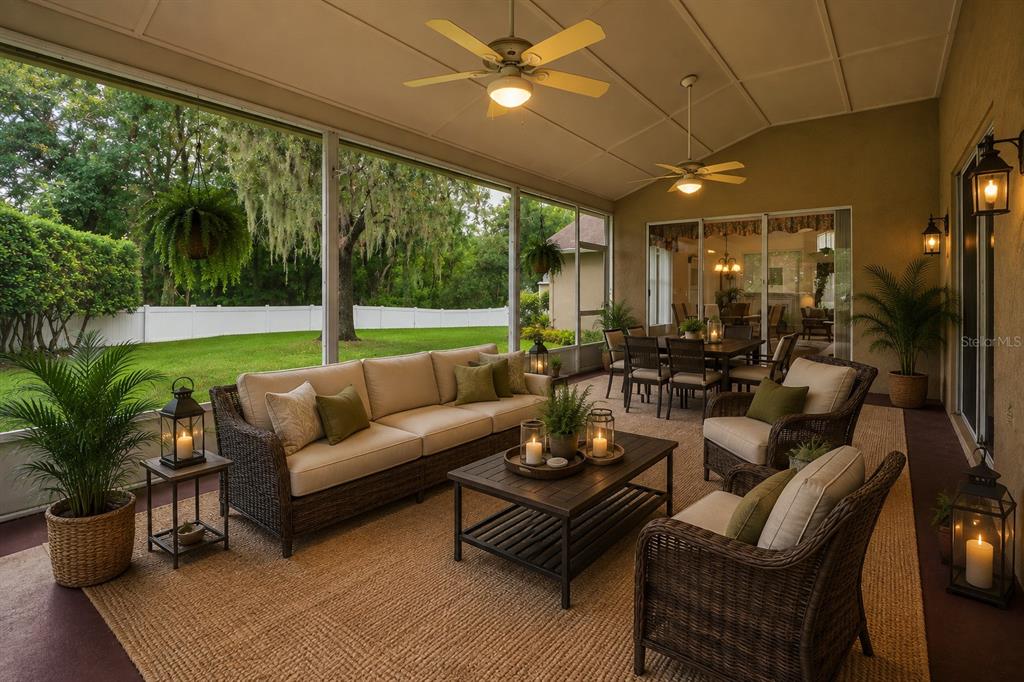 A screened-in patio features wicker furniture, a dining area, and views of a grassy backyard — 28331 OPENFIELD LOOP, WESLEY CHAPEL, FL