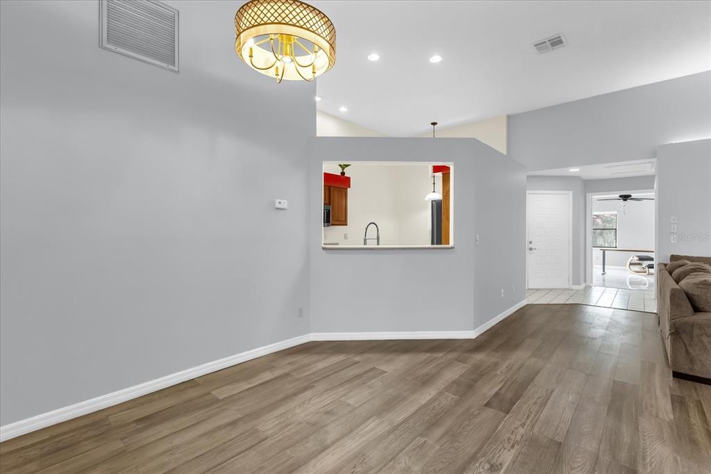 A dining area with wood-look flooring, a chandelier, and a pass-through window to the kitchen — 1313 LAKE WILLISARA CIRCLE UNIT 1313, ORLANDO, FL