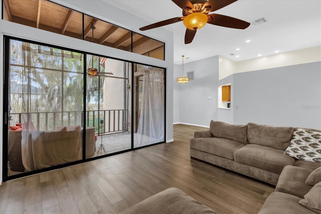 A living room features wood-look flooring, a ceiling fan, and sliding glass doors to a balcony — 1313 LAKE WILLISARA CIRCLE UNIT 1313, ORLANDO, FL