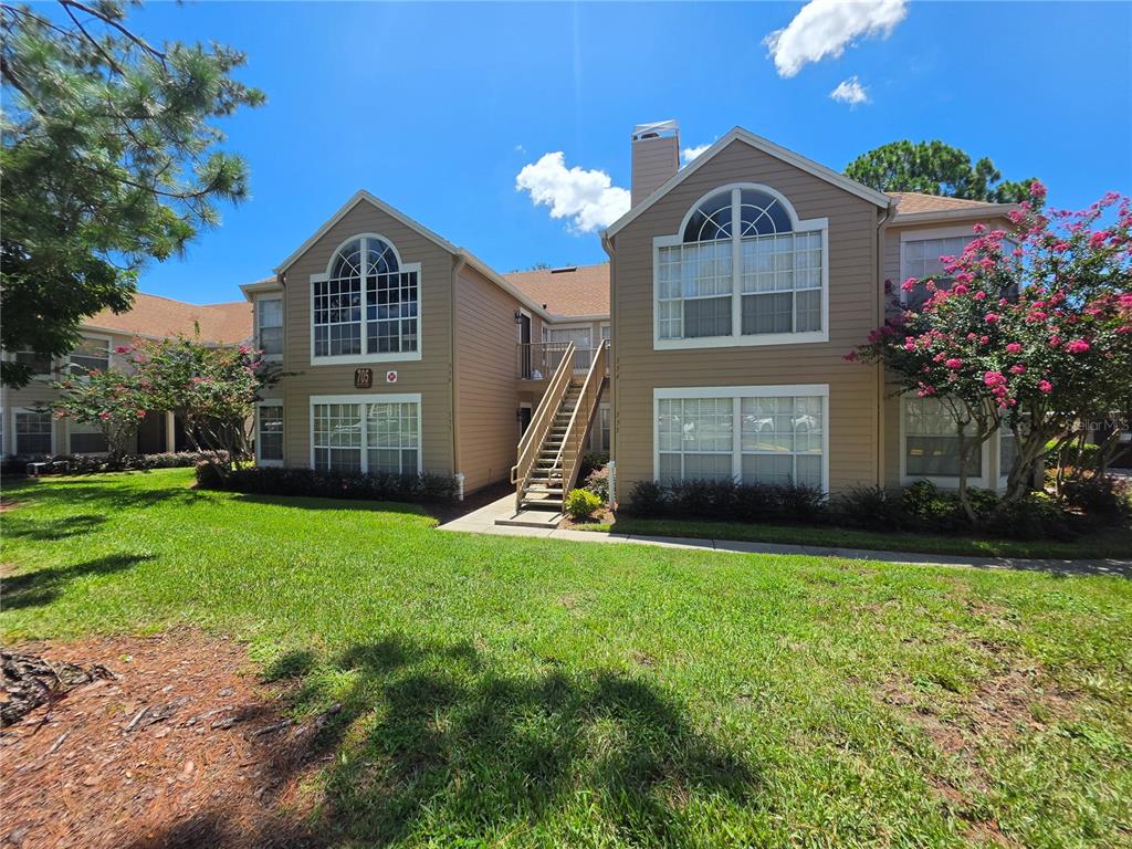 A two-story tan apartment building with a central outdoor staircase and large arched windows — 705 YOUNGSTOWN PARKWAY UNIT 356, ALTAMONTE SPRINGS, FL