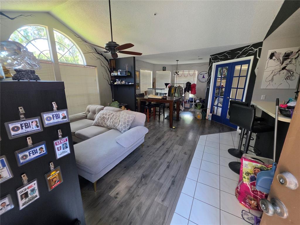 A living room features wood-look flooring, a sectional sofa, a dining table, and blue French doors — 705 YOUNGSTOWN PARKWAY UNIT 356, ALTAMONTE SPRINGS, FL