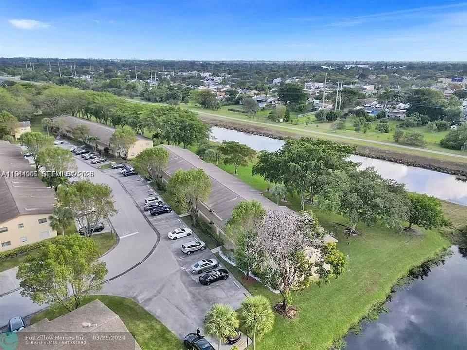 An aerial view shows multi-story apartment buildings with parking lots situated beside a canal — 7610 NW 1st St # 208, Margate FL 33063, MARGATE, FL