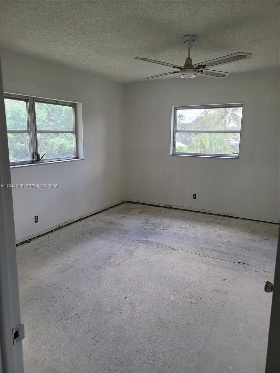 An empty bedroom features white walls, a ceiling fan, and an unfinished concrete floor — 7610 NW 1st St # 208, Margate FL 33063, MARGATE, FL