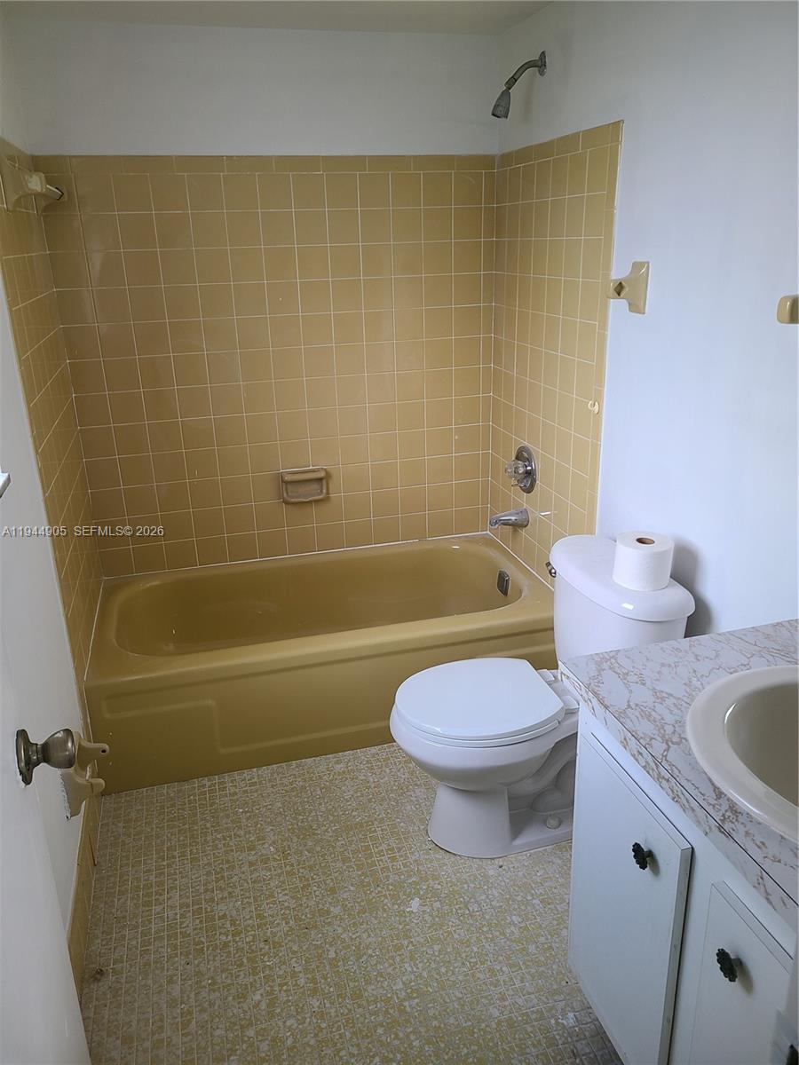 This bathroom features a yellow tiled tub surround, a matching yellow bathtub, and a vanity — 7610 NW 1st St # 208, Margate FL 33063, MARGATE, FL