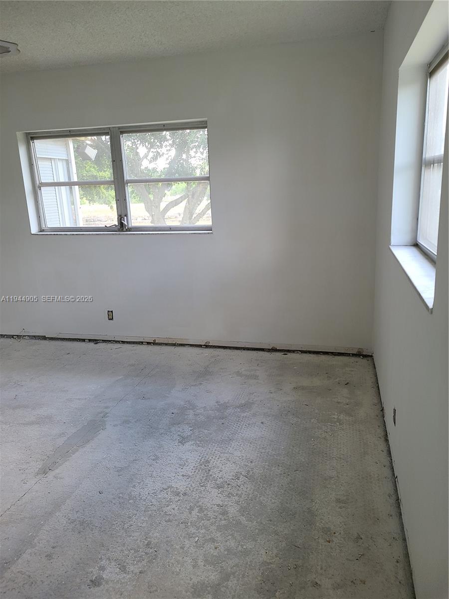 An empty room features white walls, two windows, and an unfinished concrete floor — 7610 NW 1st St # 208, Margate FL 33063, MARGATE, FL