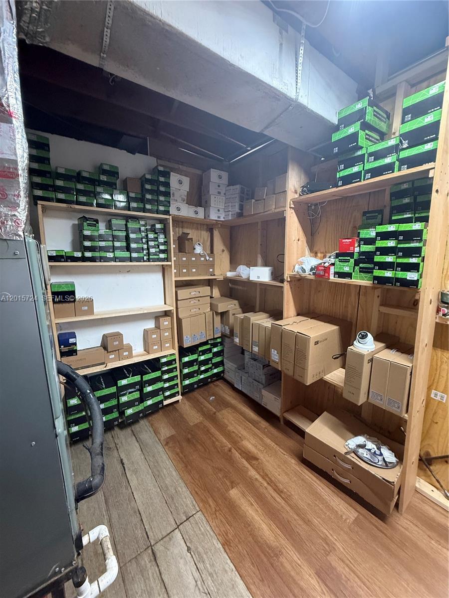 A storage room features wooden shelving units filled with numerous boxes and security camera equipment — 1775 Blount Rd # 410, Pompano Beach FL 33069, POMPANO BEACH, FL