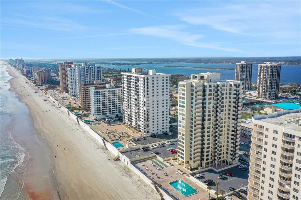 An aerial view of high-rise beachfront condominiums along a sandy coastline with swimming pools — 2987 S ATLANTIC AVENUE UNIT 205, DAYTONA BEACH SHORES, FL