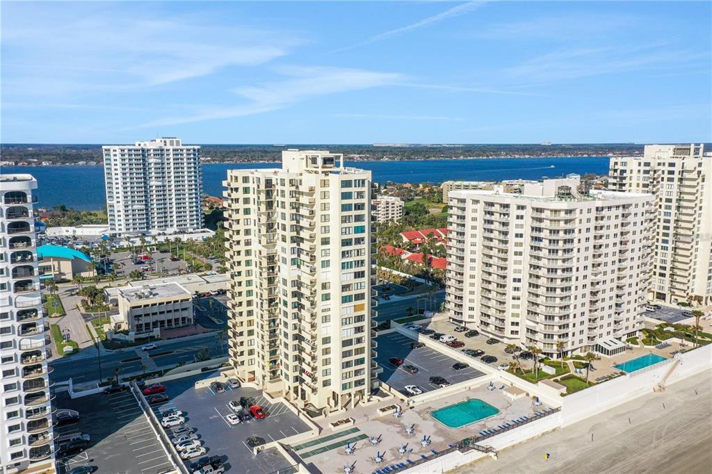 An aerial view shows several high-rise residential buildings situated along a sandy beach — 2987 S ATLANTIC AVENUE UNIT 205, DAYTONA BEACH SHORES, FL