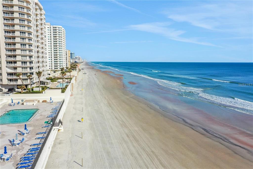 An aerial view of a sandy beach next to high-rise oceanfront condominiums and a pool — 2987 S ATLANTIC AVENUE UNIT 205, DAYTONA BEACH SHORES, FL
