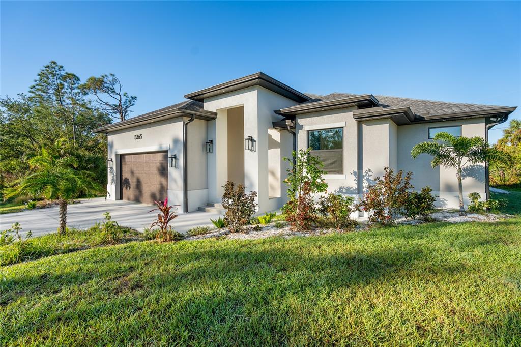 A modern single-story house with a garage, light-colored stucco exterior, and landscaped front yard — 5365 CRAIG TERRACE, PORT CHARLOTTE, FL