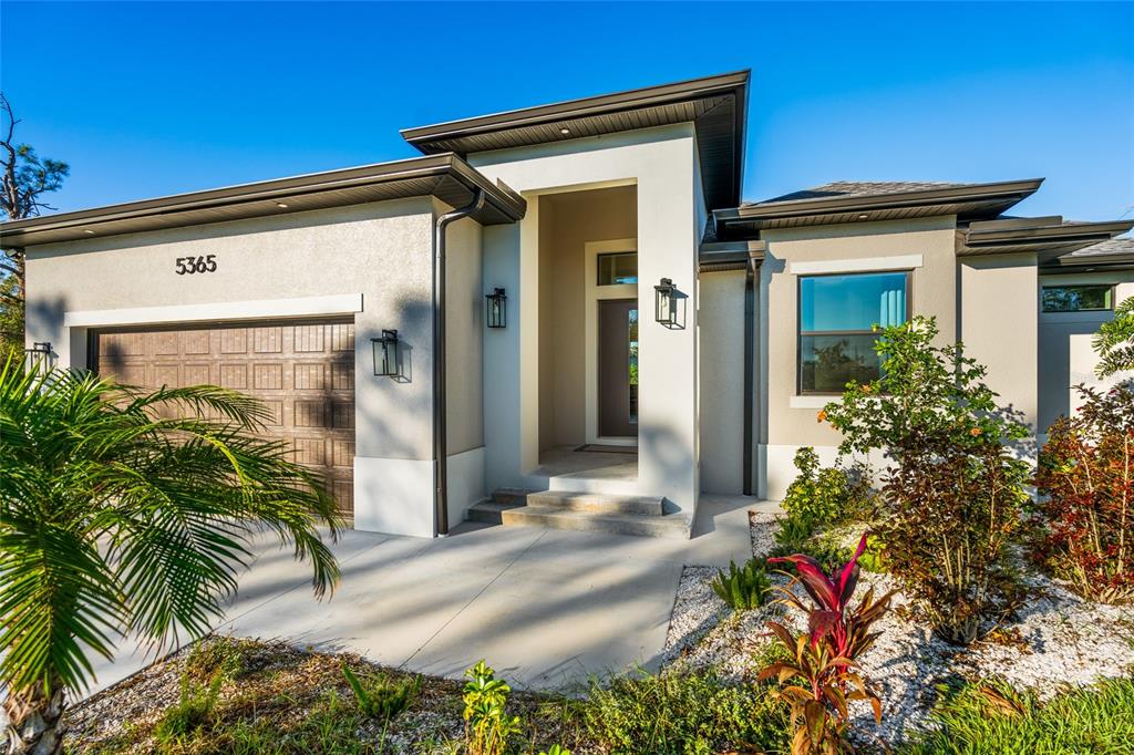 A modern single-story house exterior with a two-car garage, concrete driveway, and landscaped front yard — 5365 CRAIG TERRACE, PORT CHARLOTTE, FL